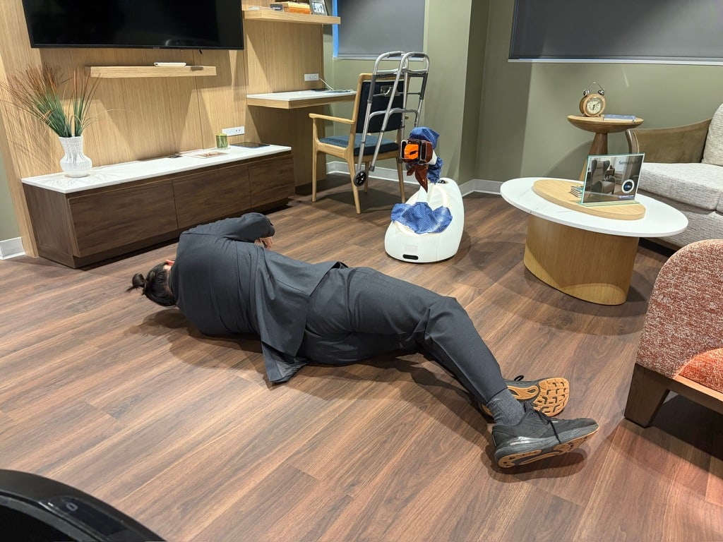 A person lies on their side on a wood floor beside a Goose prototype.