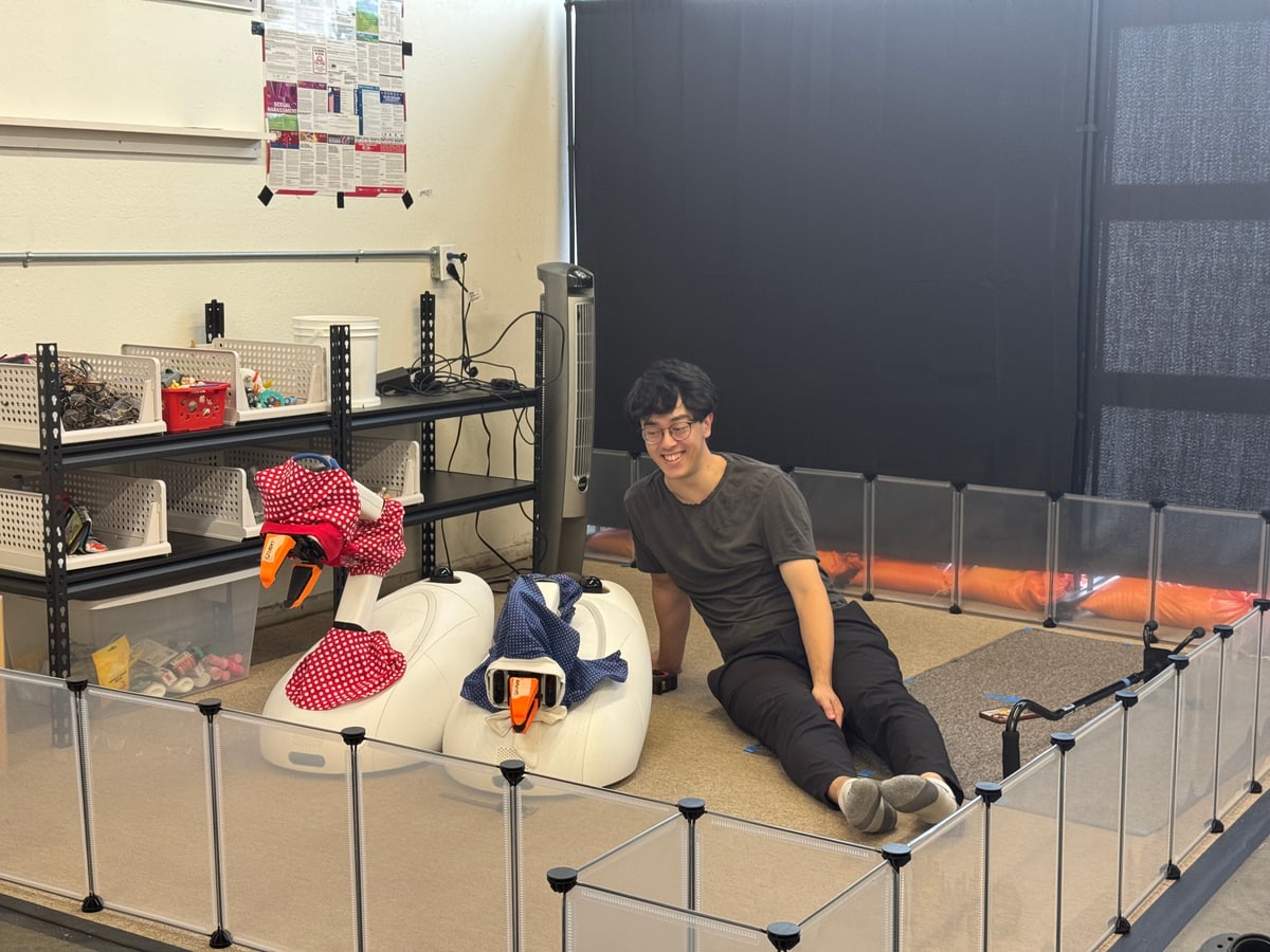 A person sits beside two Goose prototypes with red and blue fabric covers.