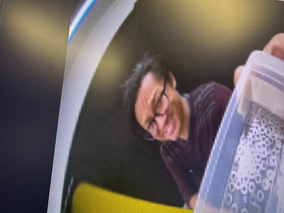 A close, tilted view of a smiling person beside a clear plastic bin.
