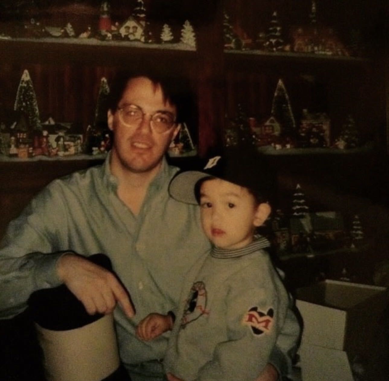 Grant Emmendorfer’s family photo: a father and young child in a ball cap beside shelves of a miniature Christmas village