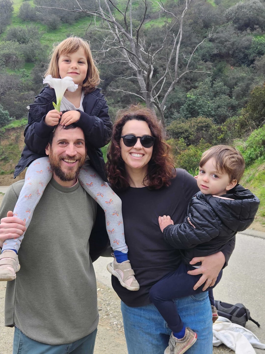 Scott Satkin with his family outdoors, carrying a child on his shoulders