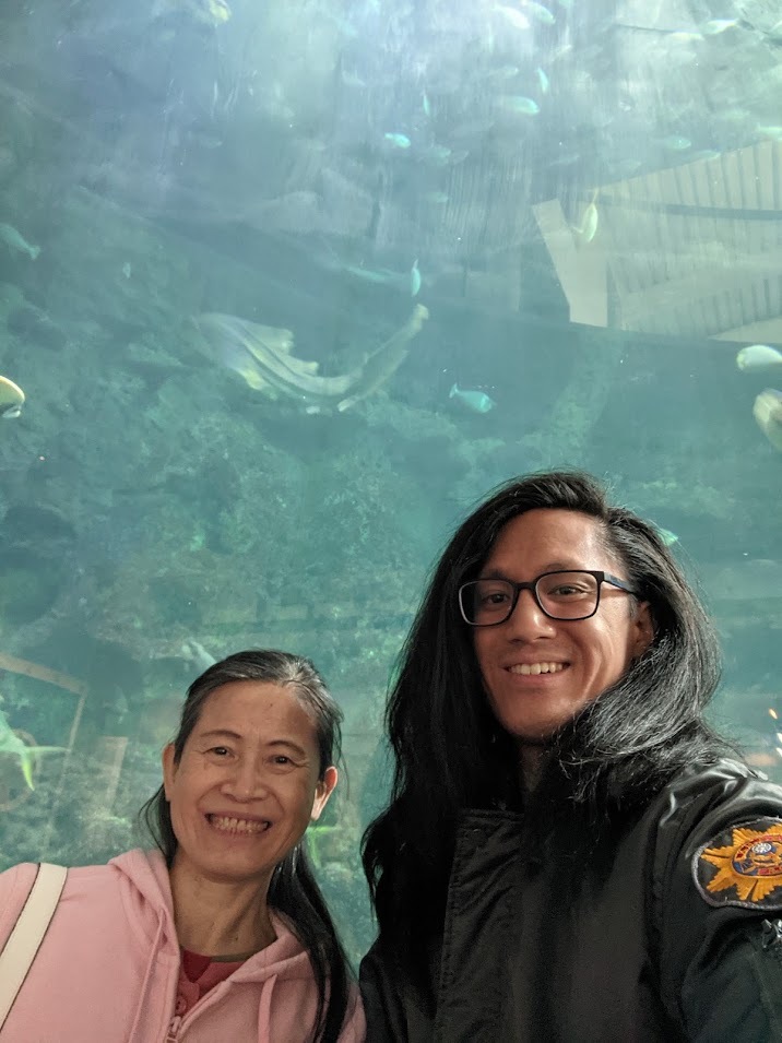 Wei Chang with their mother beneath an aquarium tunnel of fish