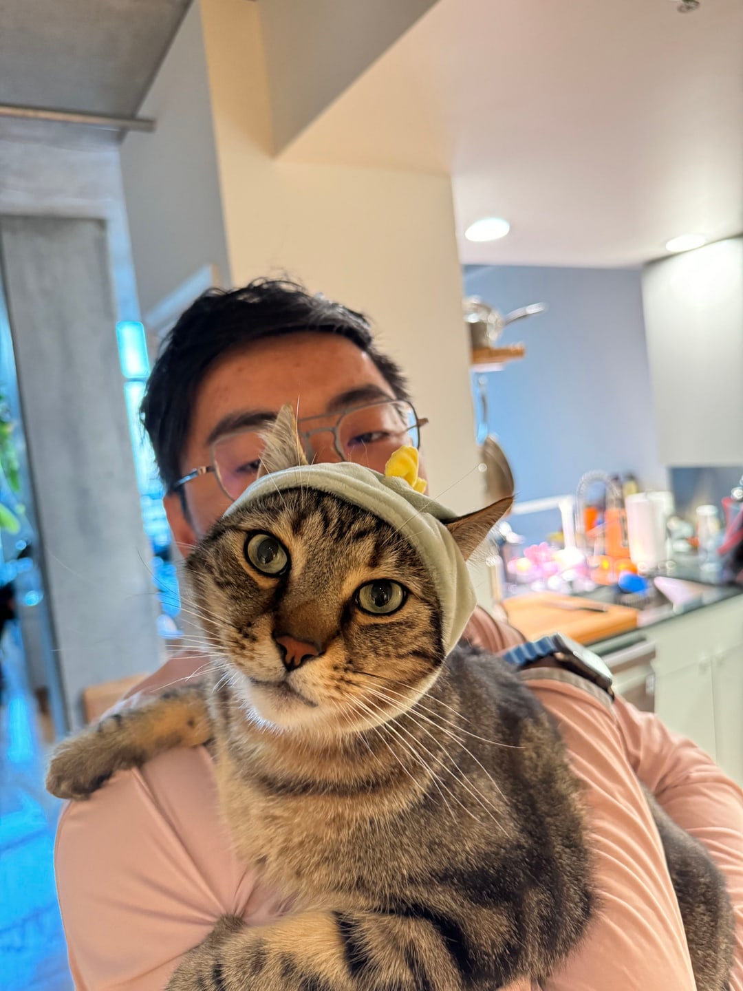 Wing Chuen Lam holding his cat Curry, who is wearing a small hood
