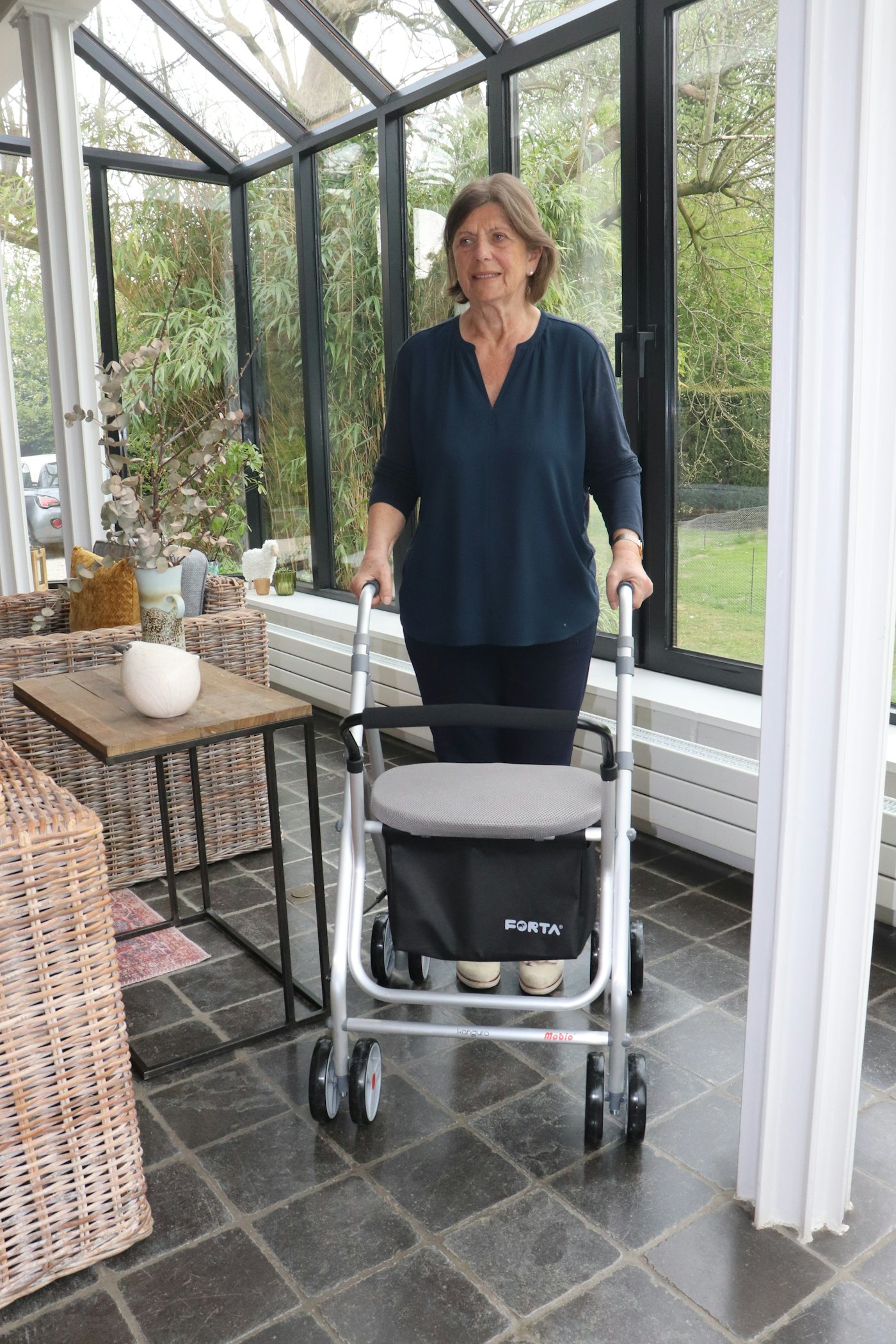 A woman with her walker in a bright sunroom