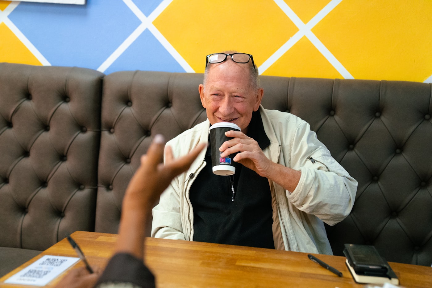 An older adult carrying a cup through the kitchen