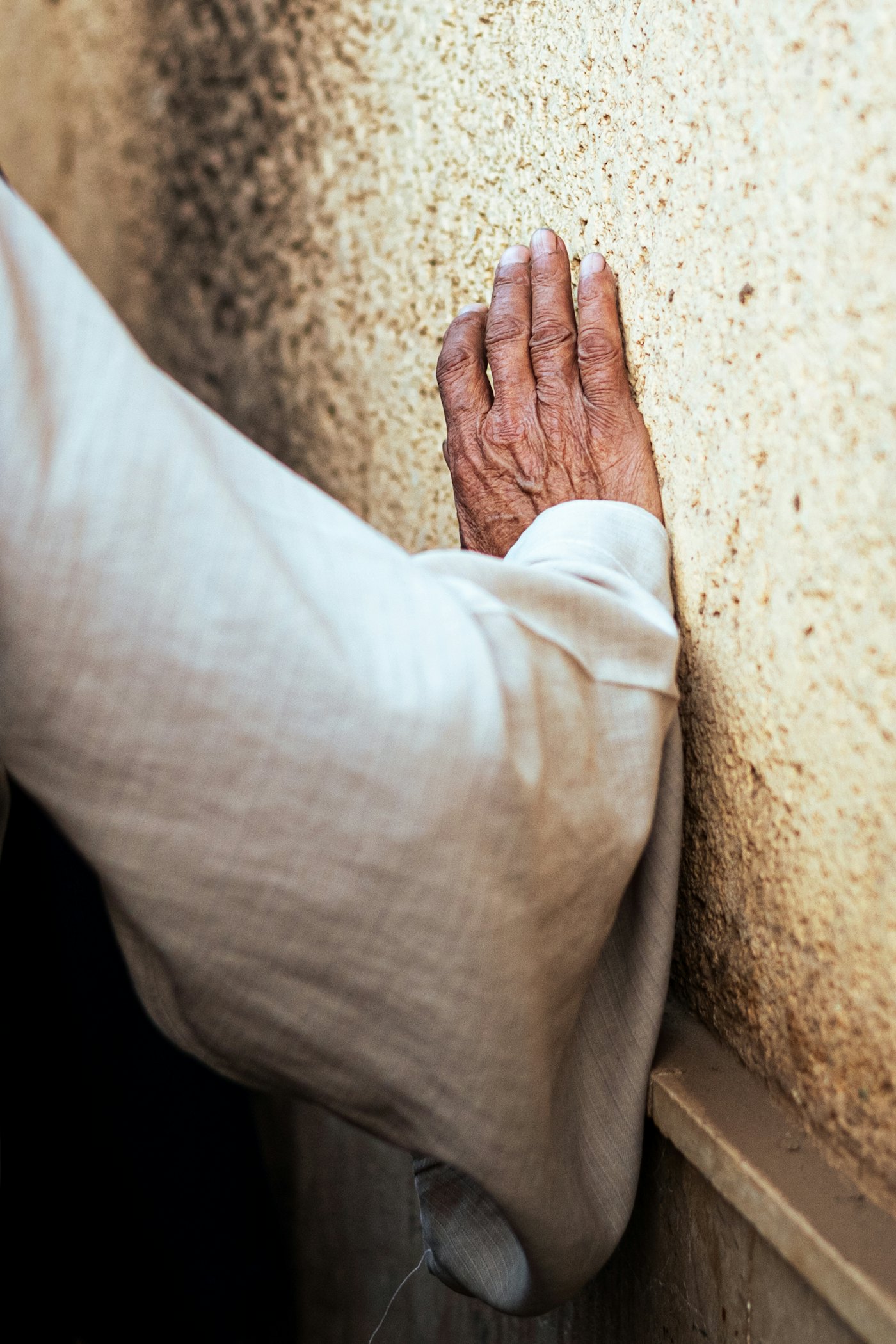 An older person steadying themselves on a kitchen counter