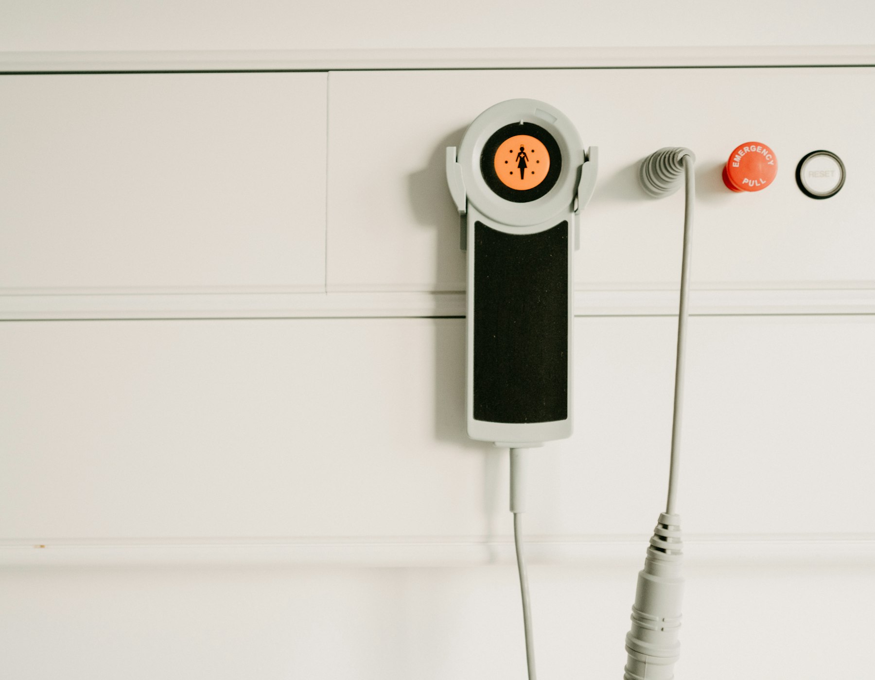A call-light panel and emergency pull cord mounted on a wall
