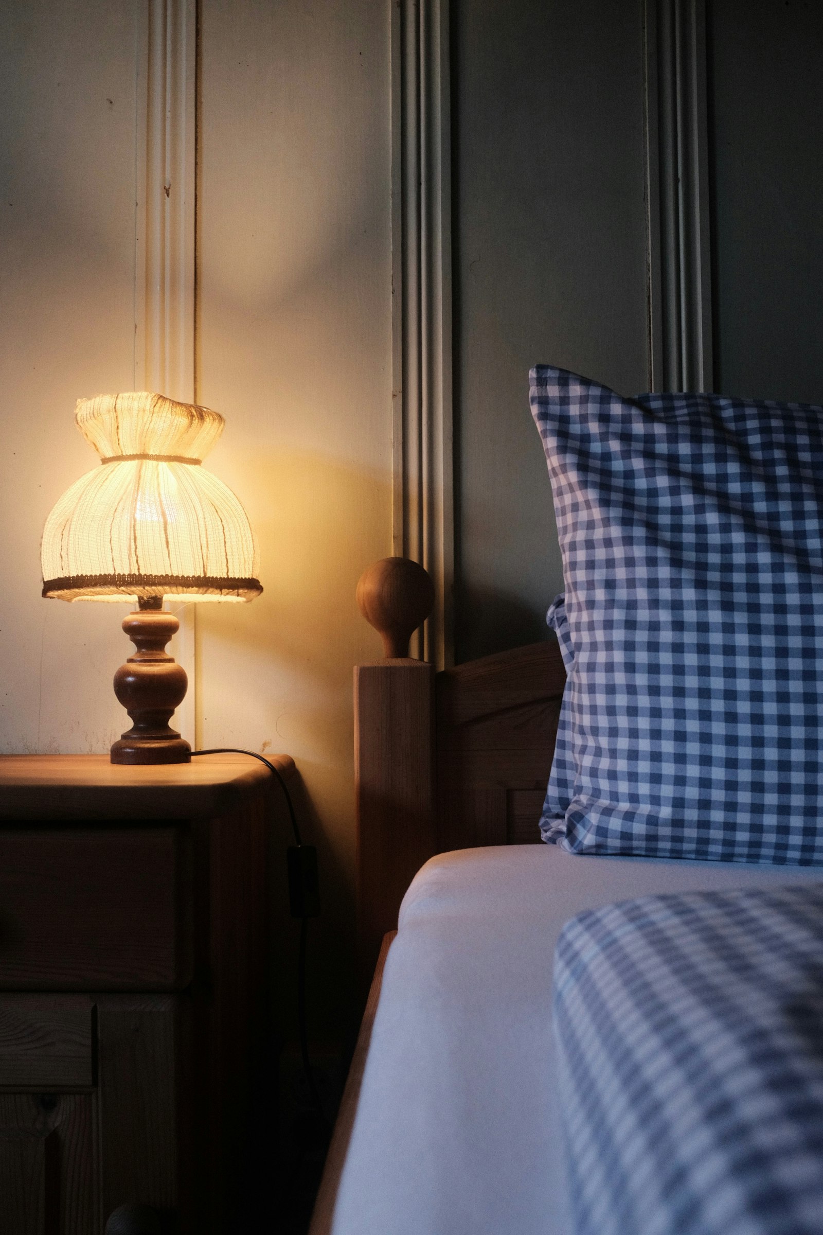 A quiet bedroom at night, lit only by a bedside lamp